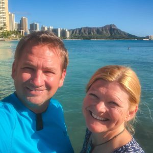 Dave and Deb of The Planet D smiling on a beach in Hawaii, ready for an adventure.