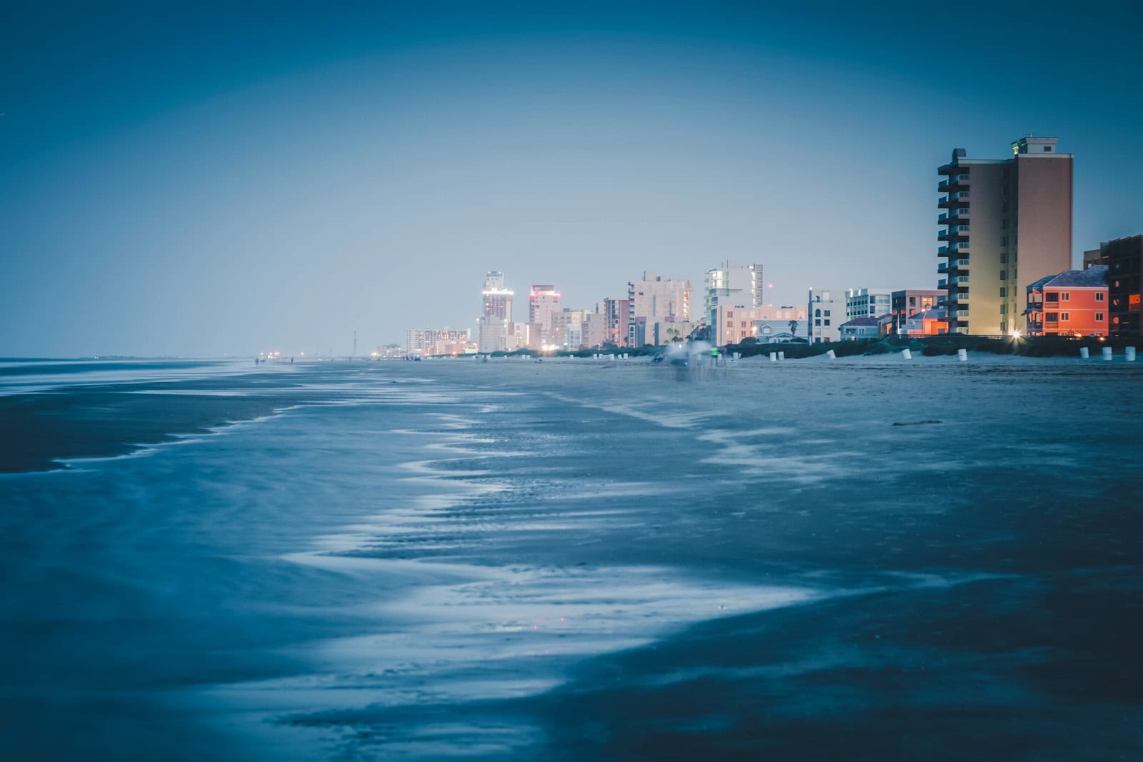 A wide, quiet beach with sand dunes on South Padre Island, a warm place to visit in December in the USA.
